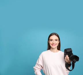 Professional photographer with modern camera on light blue background. Space for text