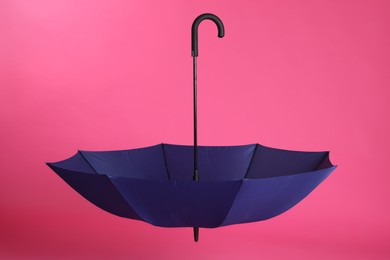 Stylish open blue umbrella on pink background