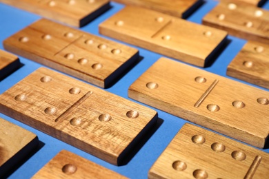 Set of wooden domino tiles on blue background, closeup