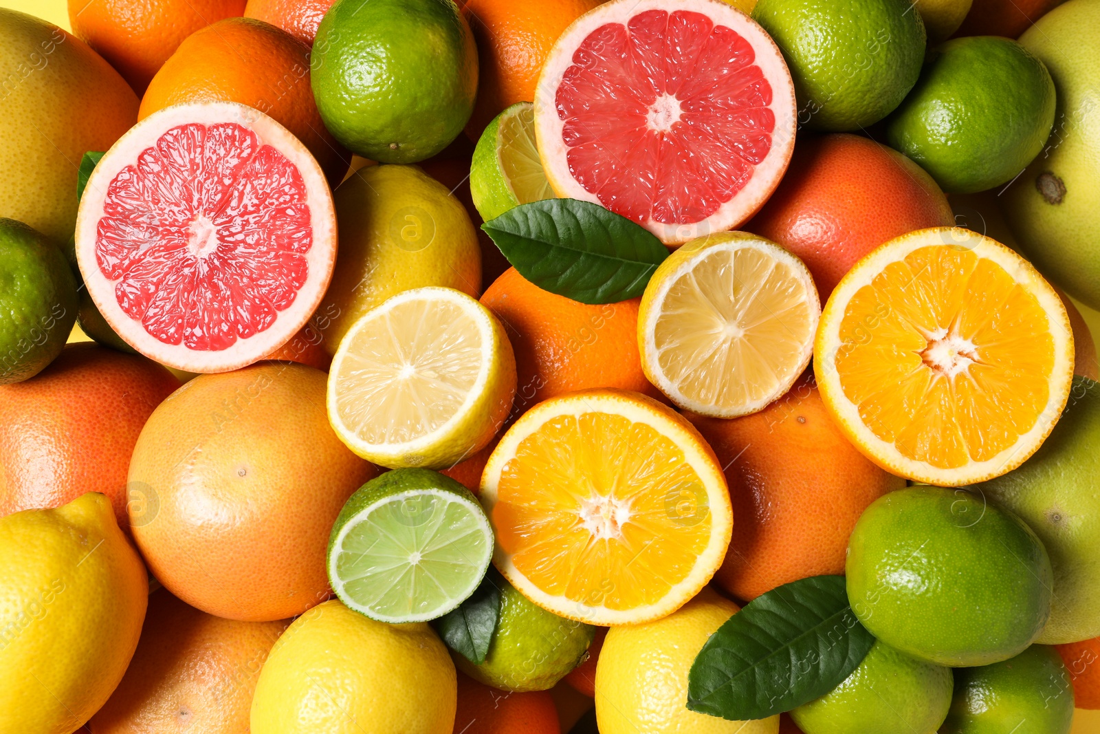 Photo of Different fresh citrus fruits and leaves as background, top view