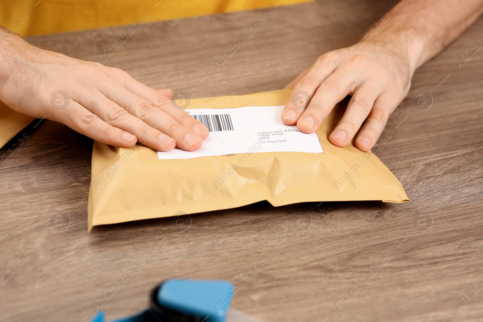 Photo of Post office worker sticking barcode on parcel at counter indoors, closeup