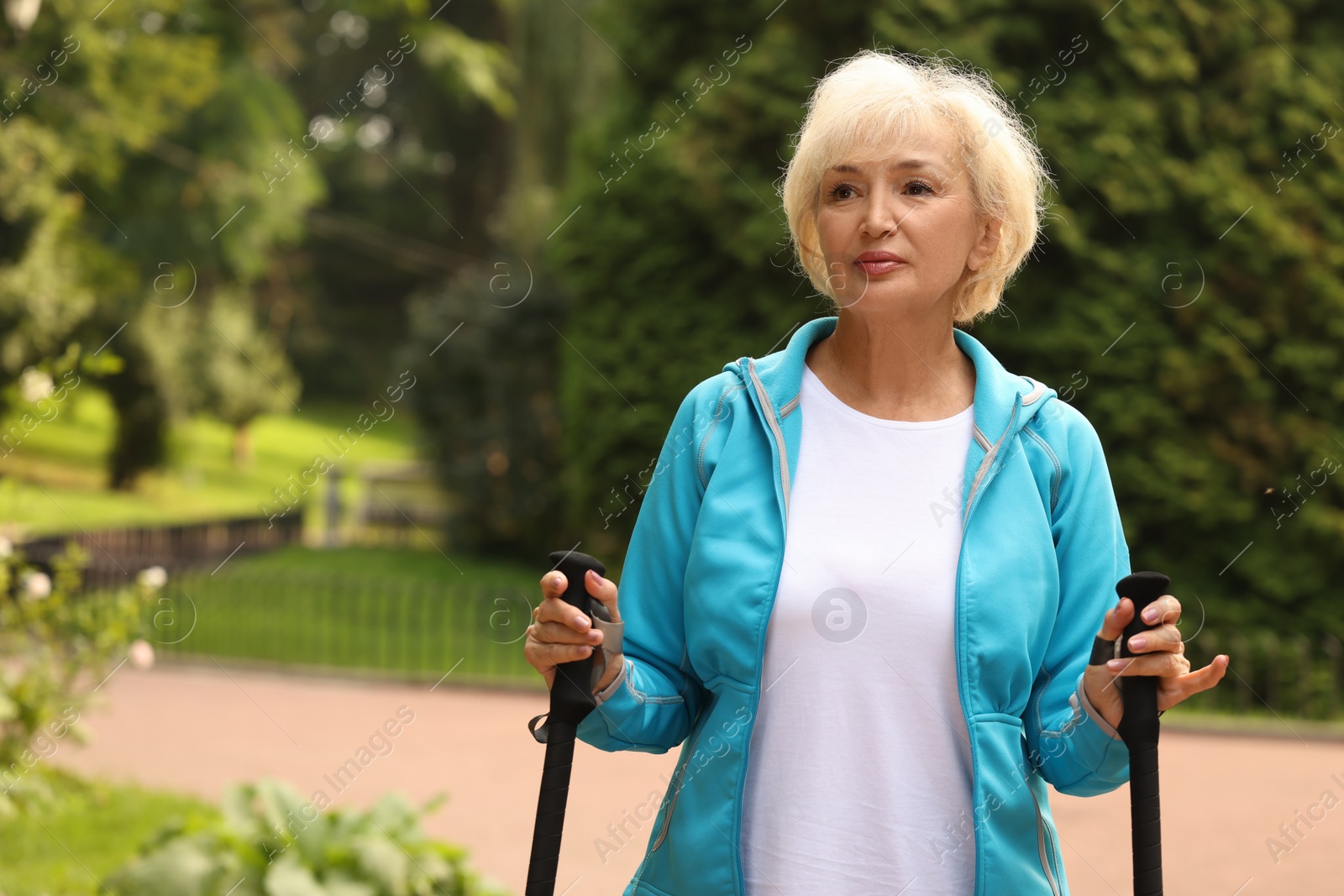 Photo of Senior woman with Nordic walking poles outdoors, space for text