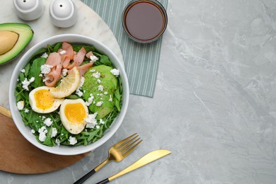 Photo of Delicious salad with boiled egg, salmon and cheese served on light grey marble table, flat lay. Space for text