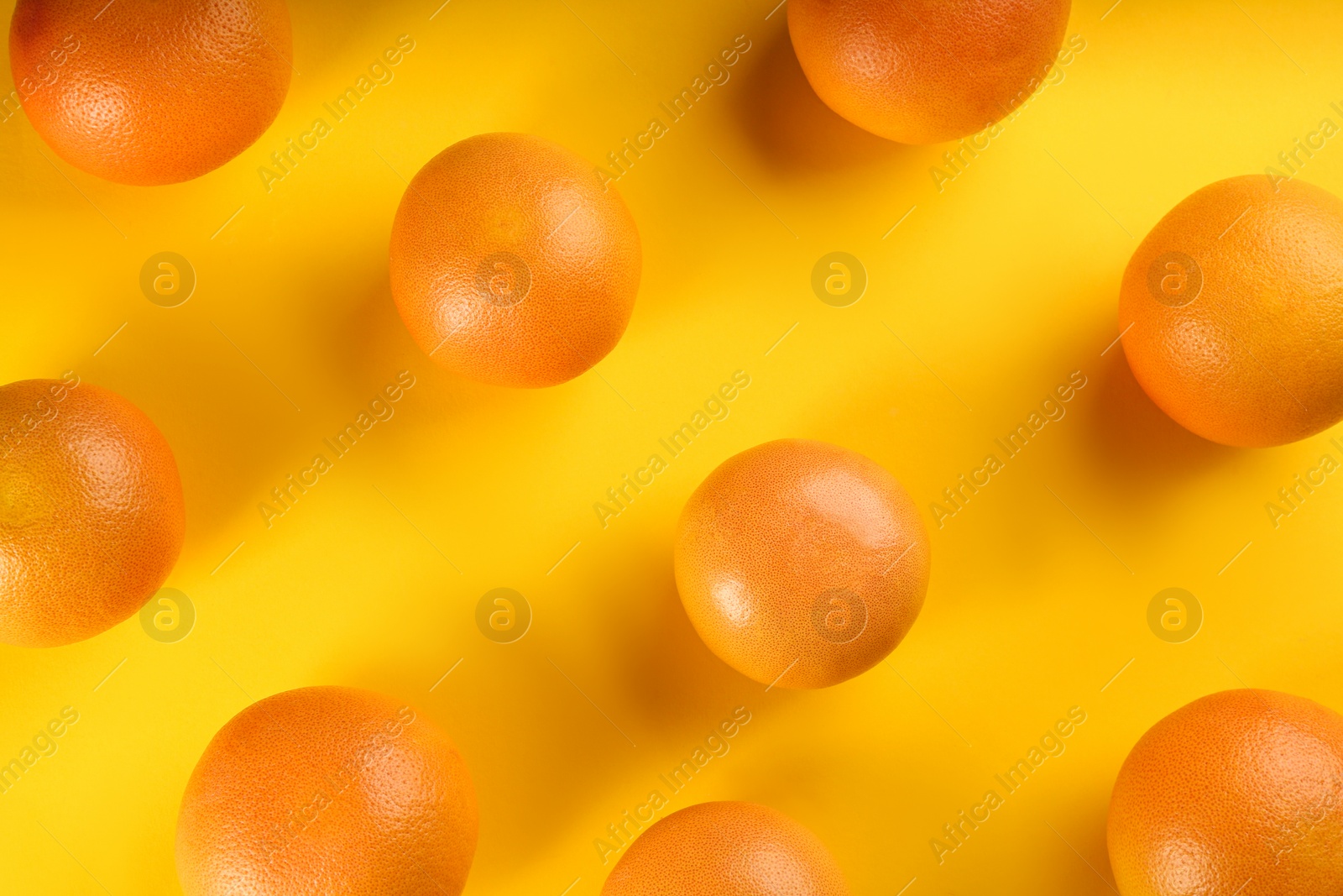 Photo of Tasty ripe grapefruits on yellow background, flat lay