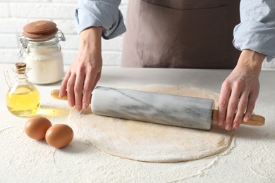 Photo of Woman rolling raw dough at table, closeup