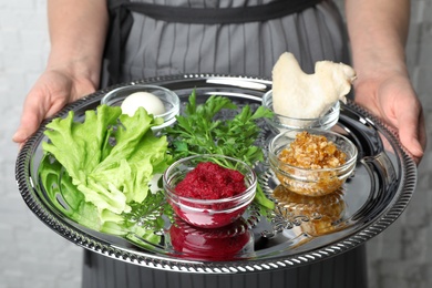Photo of Woman holding traditional Passover (Pesach) Seder plate with symbolic meal, closeup