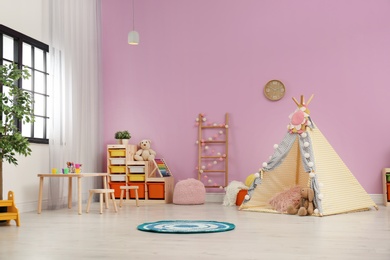 Photo of Modern nursery room interior with play tent for kids