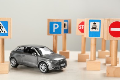 Photo of Miniature road signs and car on white table. Driving school