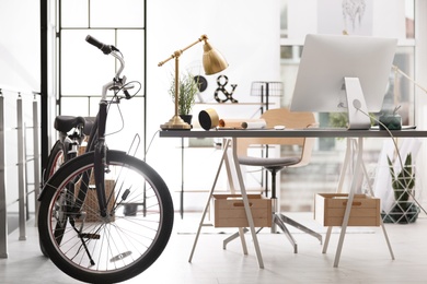 Stylish office interior with comfortable workplace and bicycle
