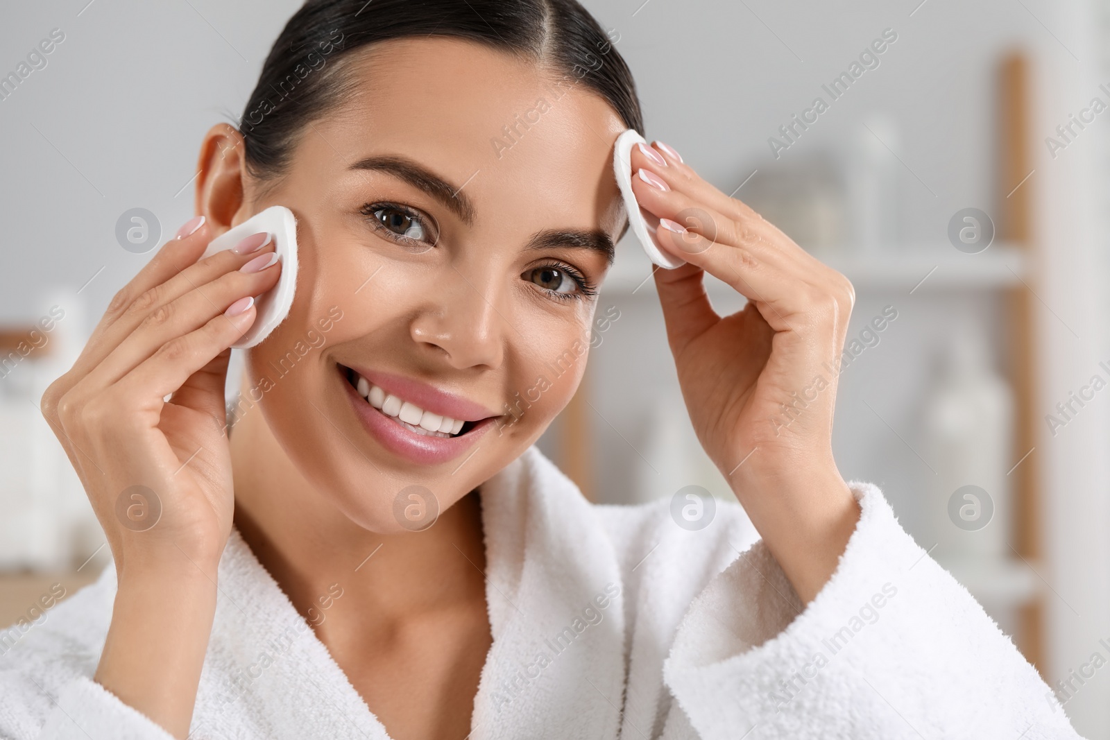 Photo of Beautiful woman removing makeup with cotton pads indoors