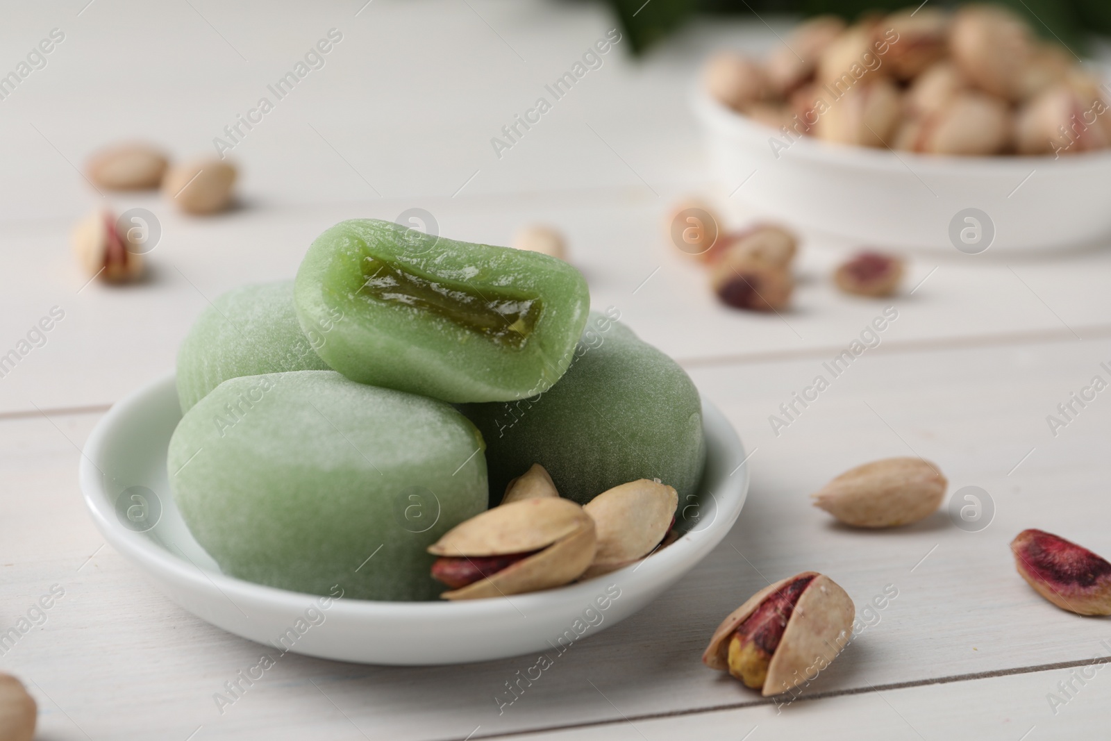 Photo of Delicious mochi and pistachios on white wooden table, closeup with space for text. Traditional Japanese dessert