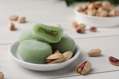 Delicious mochi and pistachios on white wooden table, closeup with space for text. Traditional Japanese dessert