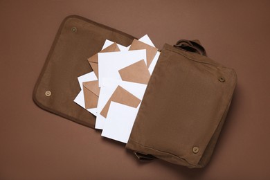 Photo of Postman bag with mails on brown background, top view