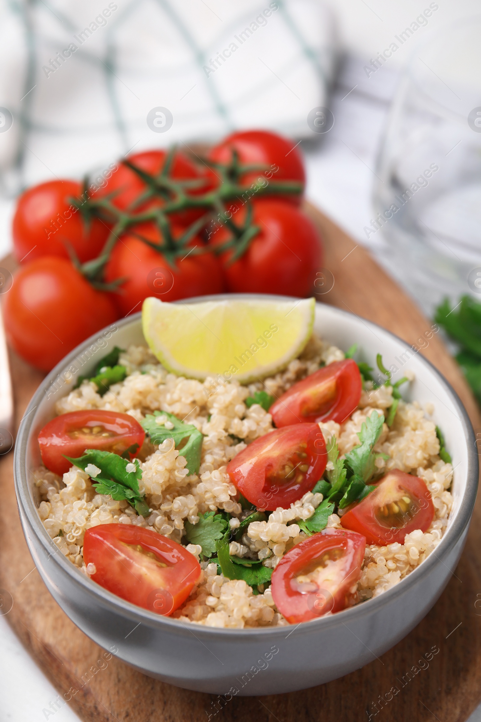 Photo of Delicious quinoa salad with tomatoes, parsley and lime served on white wooden table