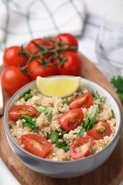 Delicious quinoa salad with tomatoes, parsley and lime served on white wooden table