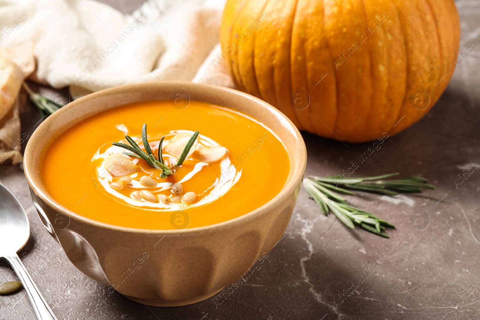 Photo of Delicious pumpkin soup in bowl on marble table