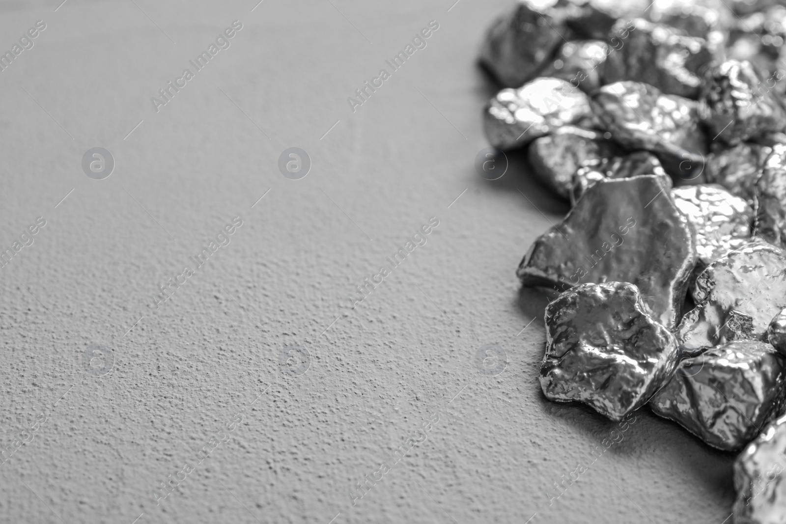 Photo of Pile of silver nuggets on grey table, closeup. Space for text