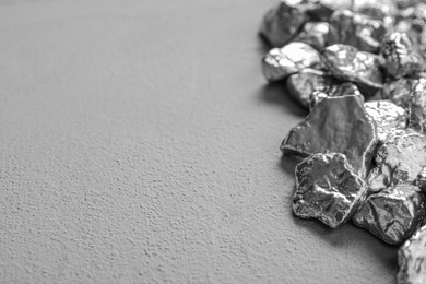 Photo of Pile of silver nuggets on grey table, closeup. Space for text