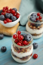 Photo of Delicious yogurt parfait with fresh berries on turquoise wooden table, closeup