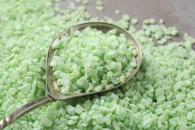 Spoon with light green sea salt on grey table, closeup