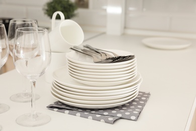 Photo of Clean dishes, glasses and cutlery on table in kitchen