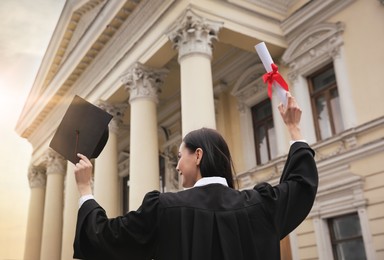 Photo of Student with diploma after graduation ceremony outdoors, low angle view