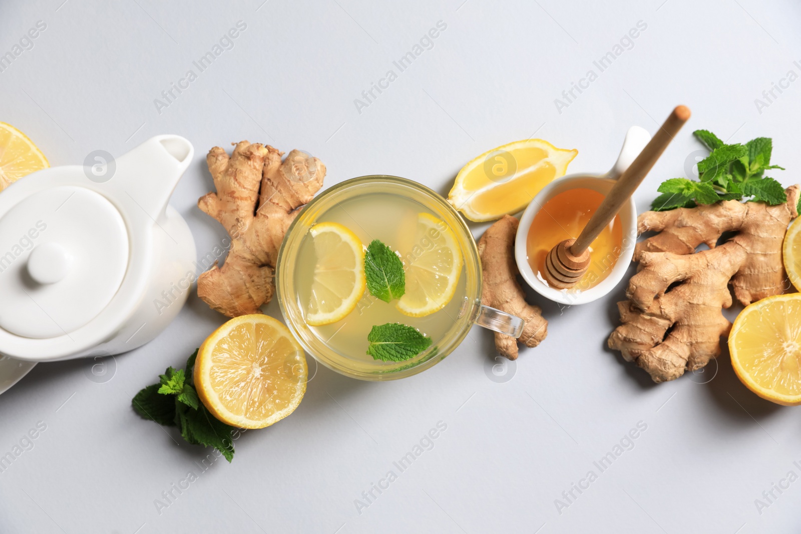 Photo of Delicious ginger tea and ingredients on light grey background, flat lay