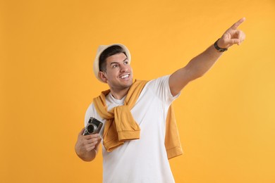 Male tourist with camera on yellow background