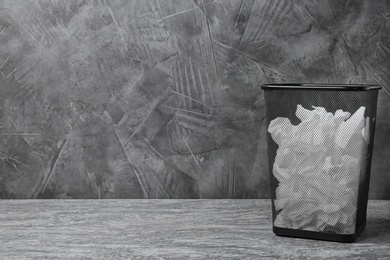 Trash bin with used toilet paper on floor near grey wall. Space for text