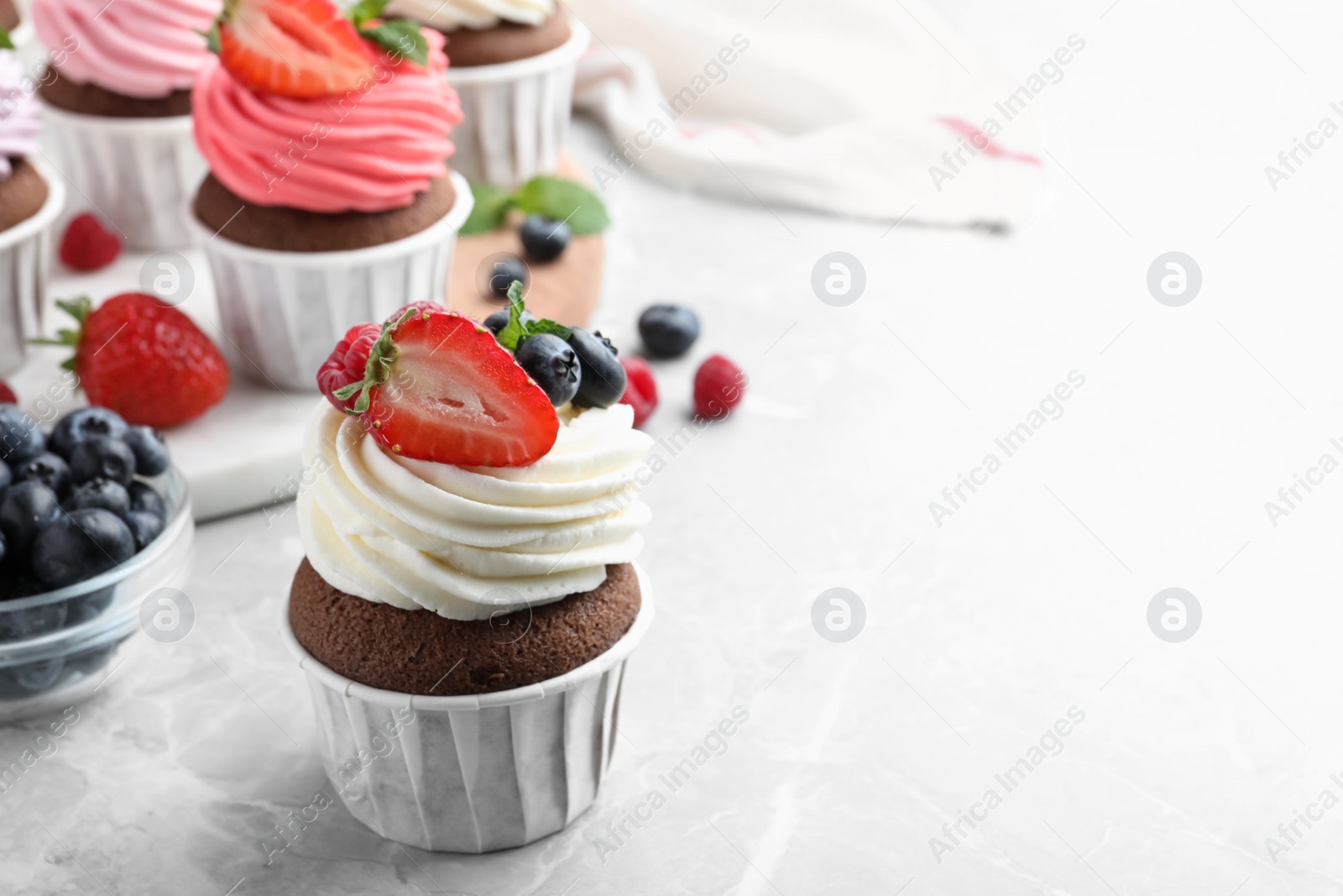 Photo of Sweet cupcake with fresh berries on light marble table. Space for text