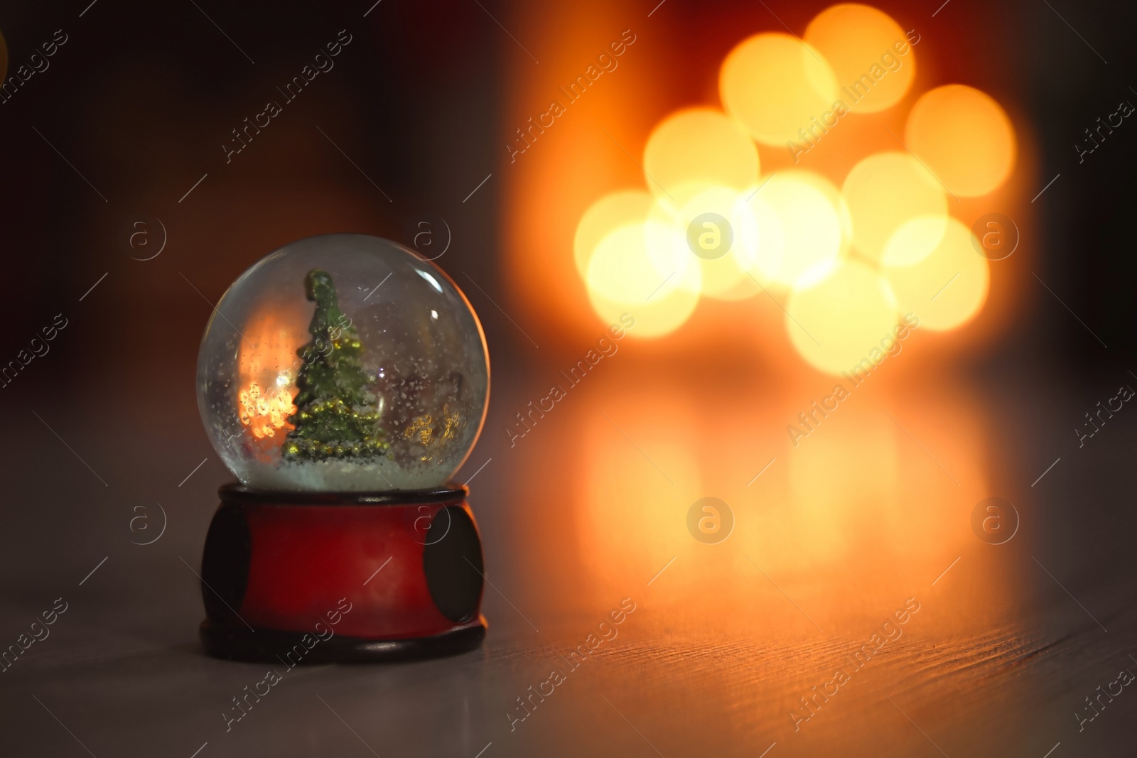 Photo of Snow globe on wooden table against blurred background, space for text. Bokeh effect