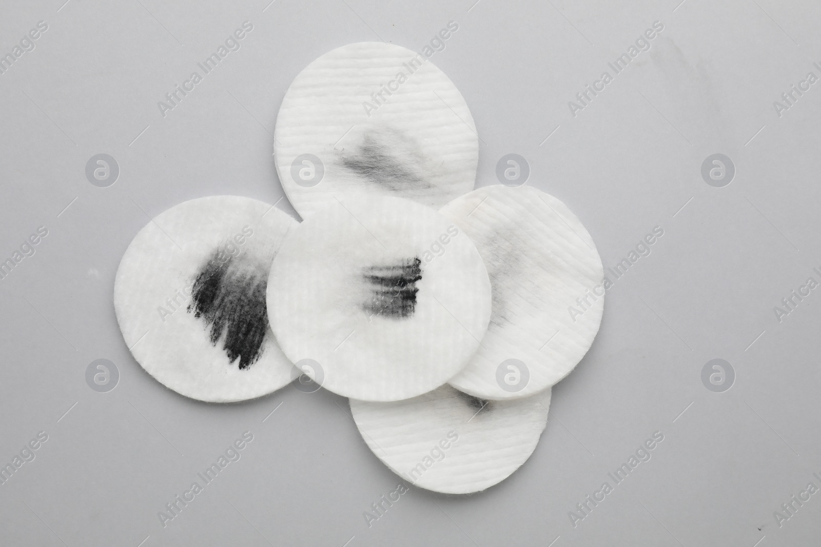 Photo of Dirty cotton pads after removing makeup on light grey background, flat lay