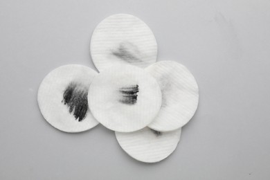 Photo of Dirty cotton pads after removing makeup on light grey background, flat lay