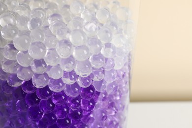 Photo of Different color fillers in glass vase, closeup. Water beads
