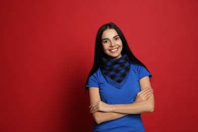 Young woman wearing stylish bandana on red background, space for text