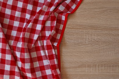 Checkered picnic cloth on wooden table, top view. Space for text