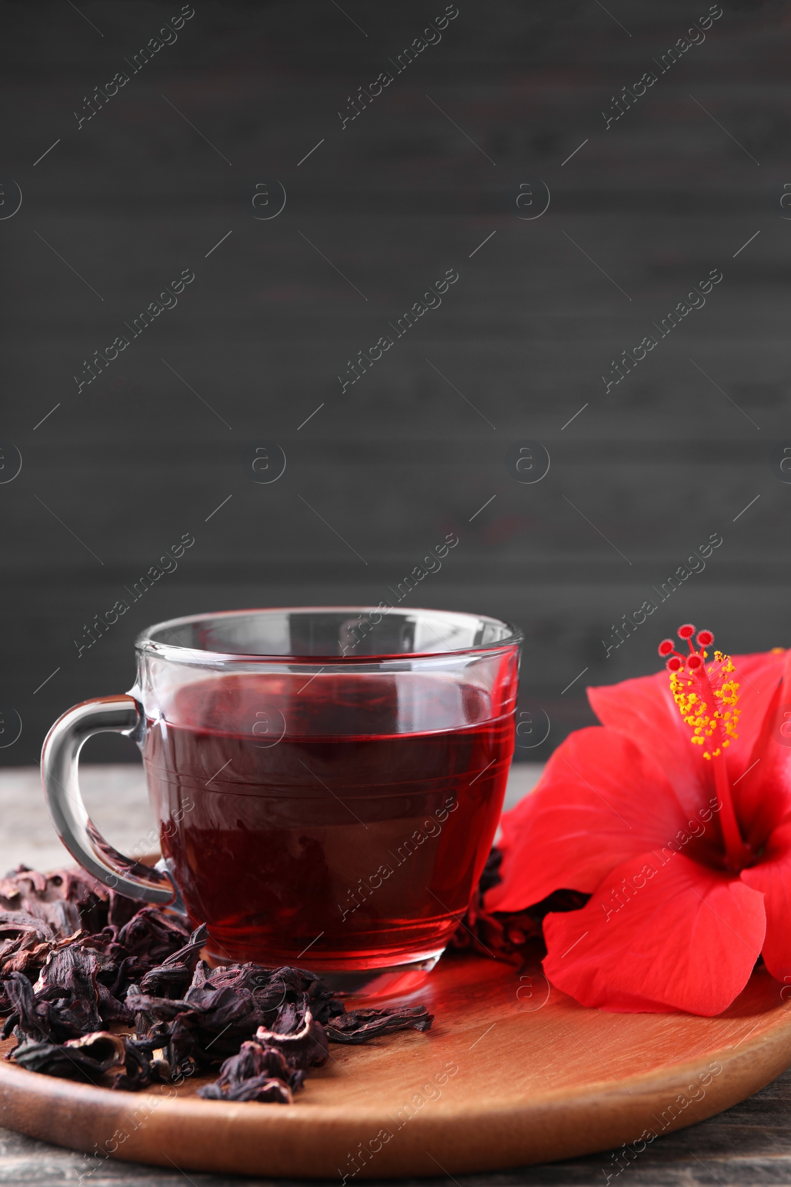 Photo of Delicious hibiscus tea and flowers on table, space for text