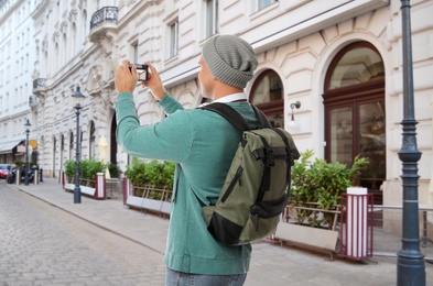 Image of Traveler with backpack taking photo in foreign city during vacation