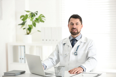 Portrait of male doctor in white coat at workplace