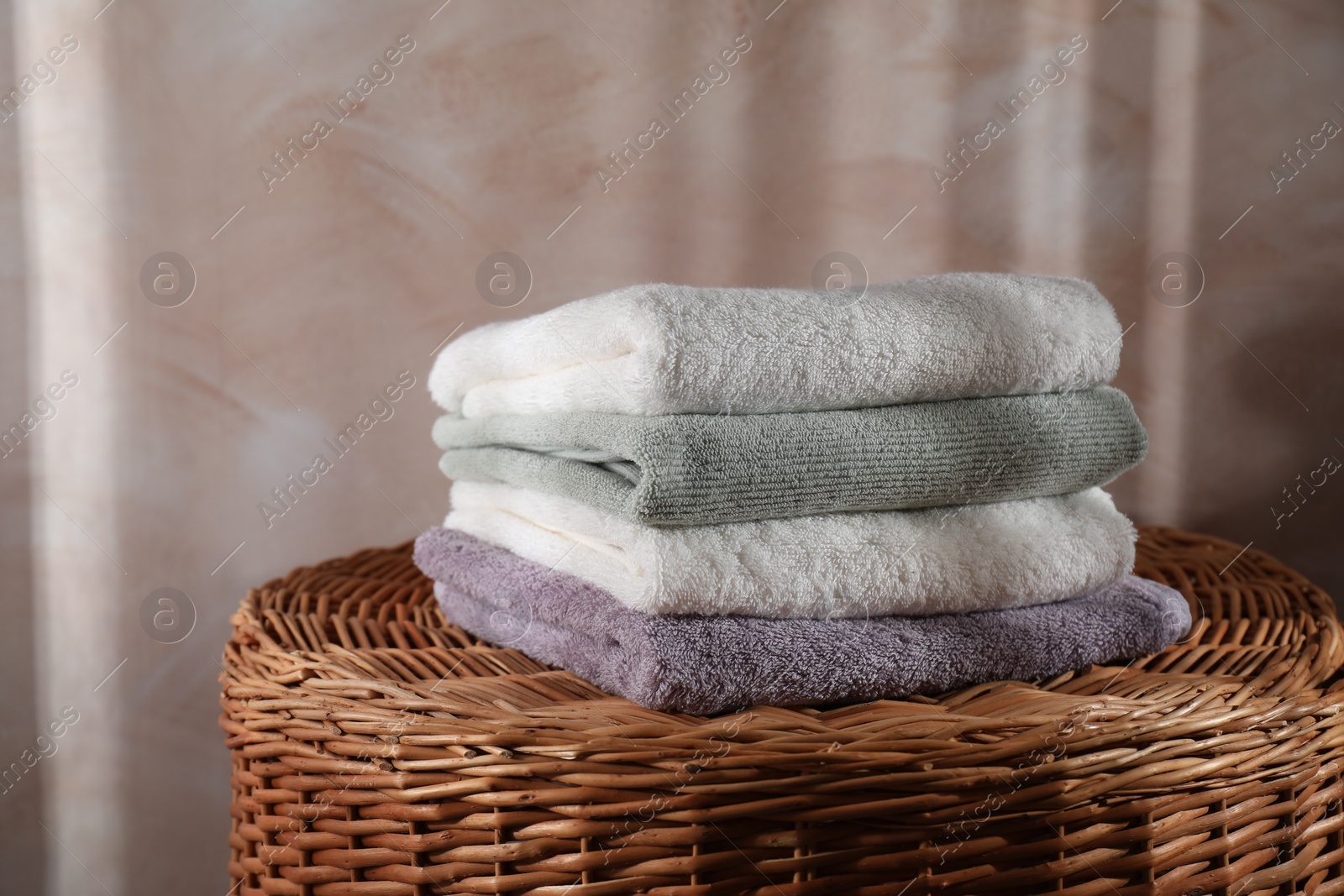 Photo of Stacked soft towels on rattan laundry basket indoors
