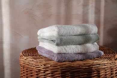 Photo of Stacked soft towels on rattan laundry basket indoors