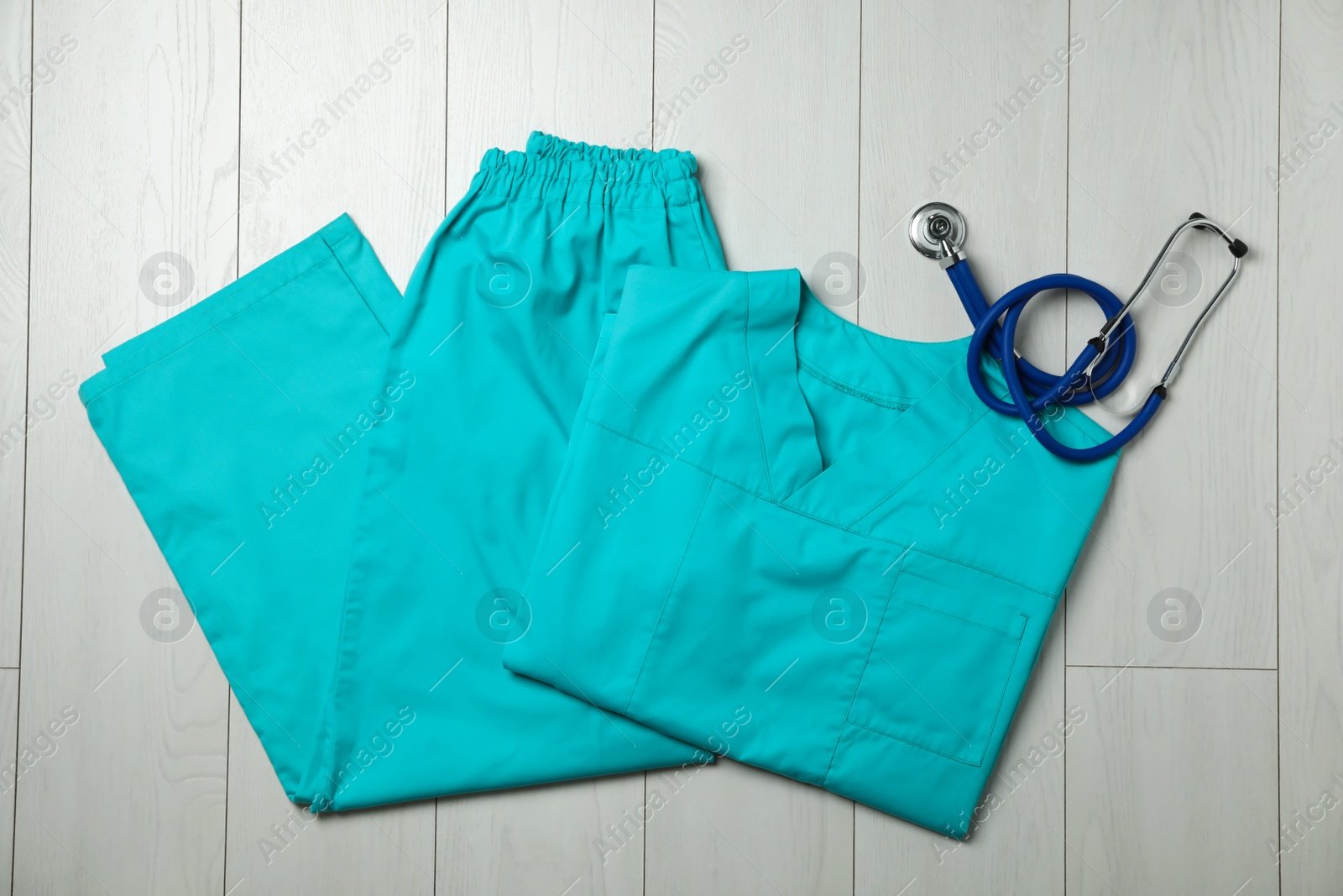 Photo of Clean scrubs and stethoscope on wooden background, top view. Medical objects