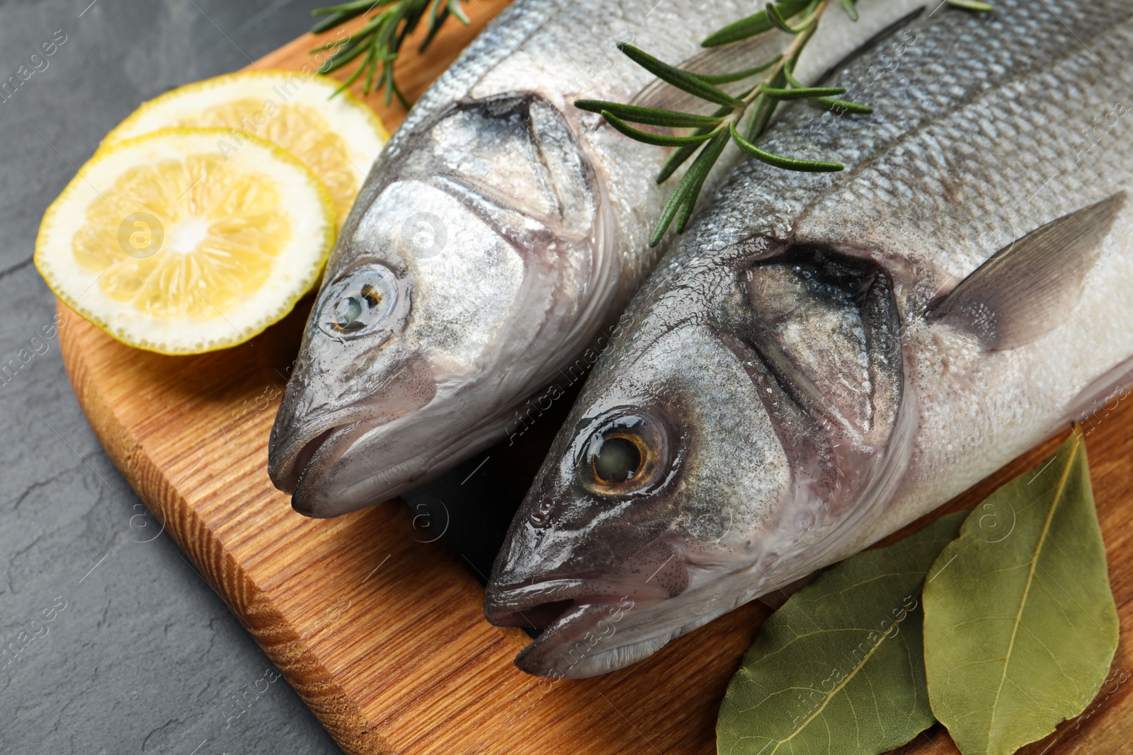 Photo of Tasty sea bass fish on dark grey textured table, closeup