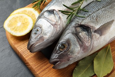 Photo of Tasty sea bass fish on dark grey textured table, closeup