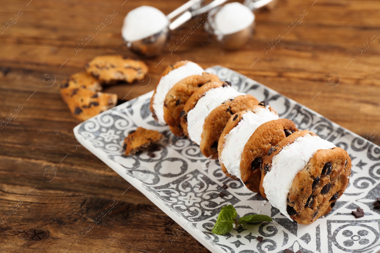 Photo of Sweet delicious ice cream cookie sandwiches on wooden table