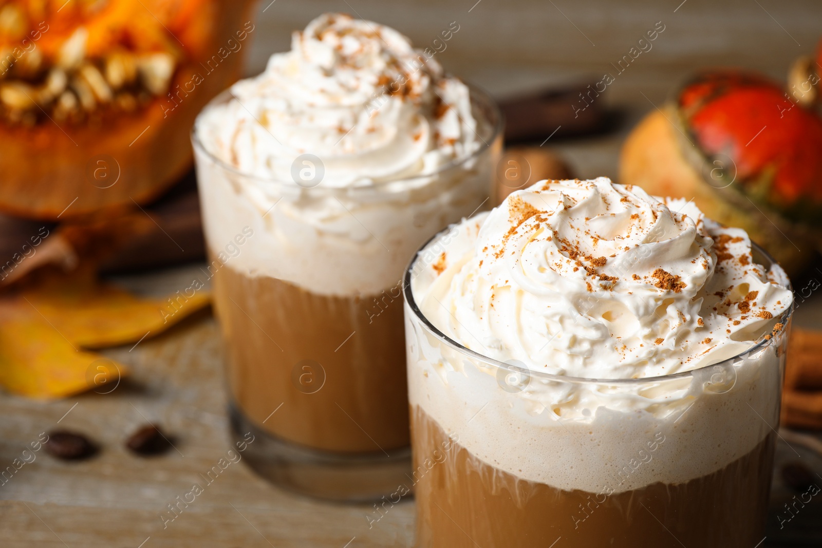 Photo of Glasses with tasty pumpkin spice latte on wooden table, closeup