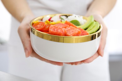 Woman holding delicious poke bowl with salmon, avocado and vegetables, closeup