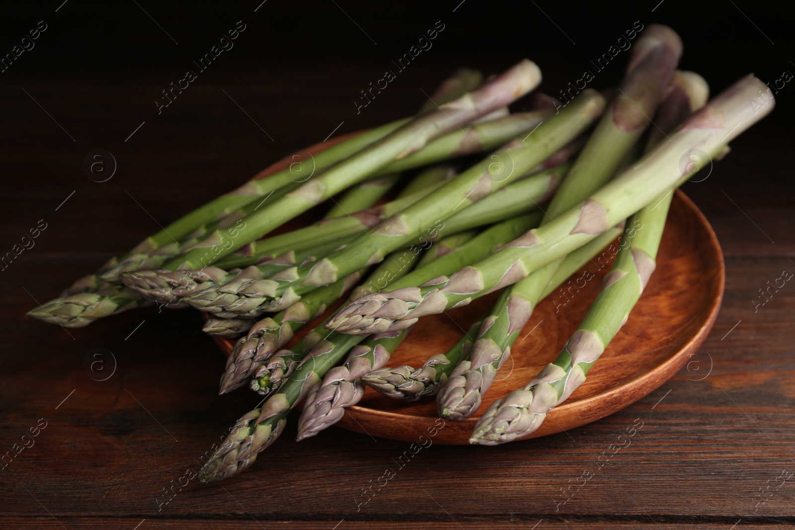 Photo of Fresh raw asparagus on wooden table, closeup