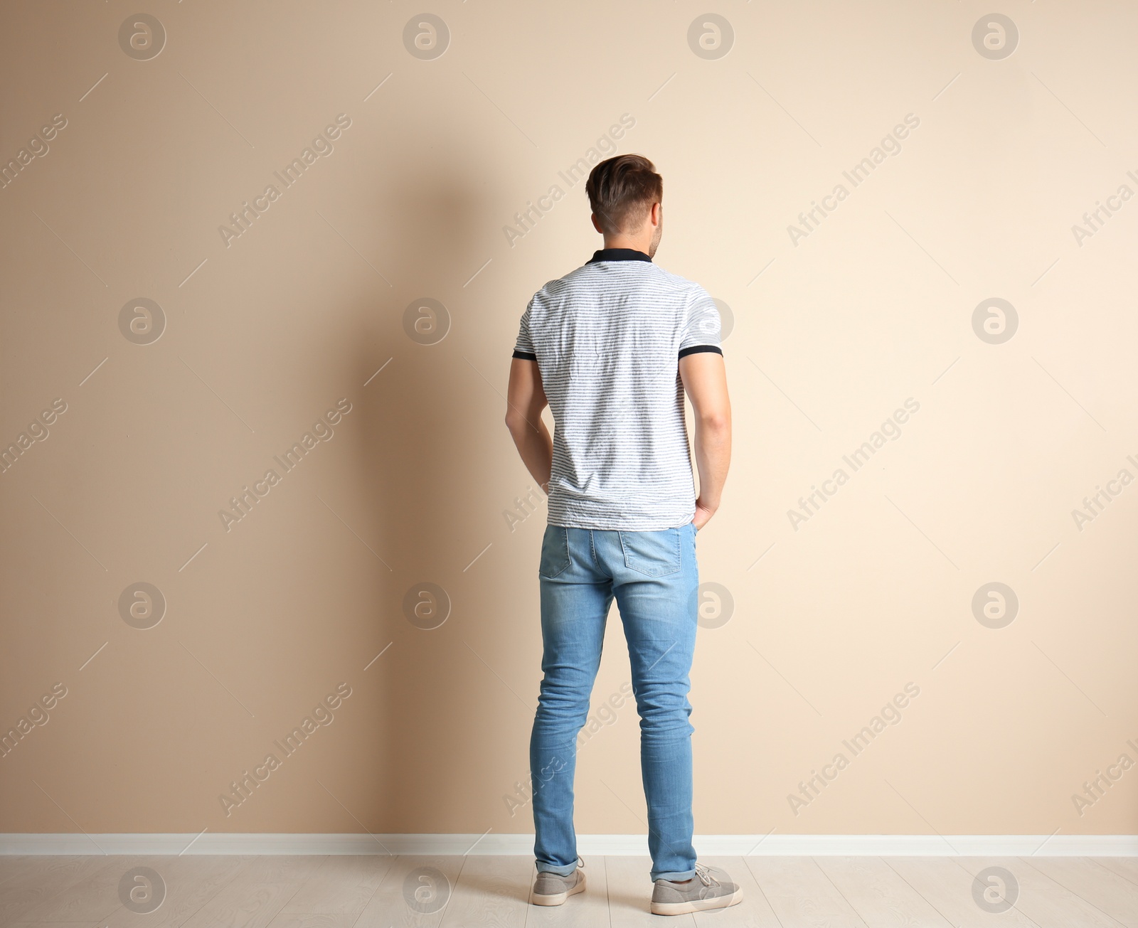 Photo of Young man in stylish jeans near light wall