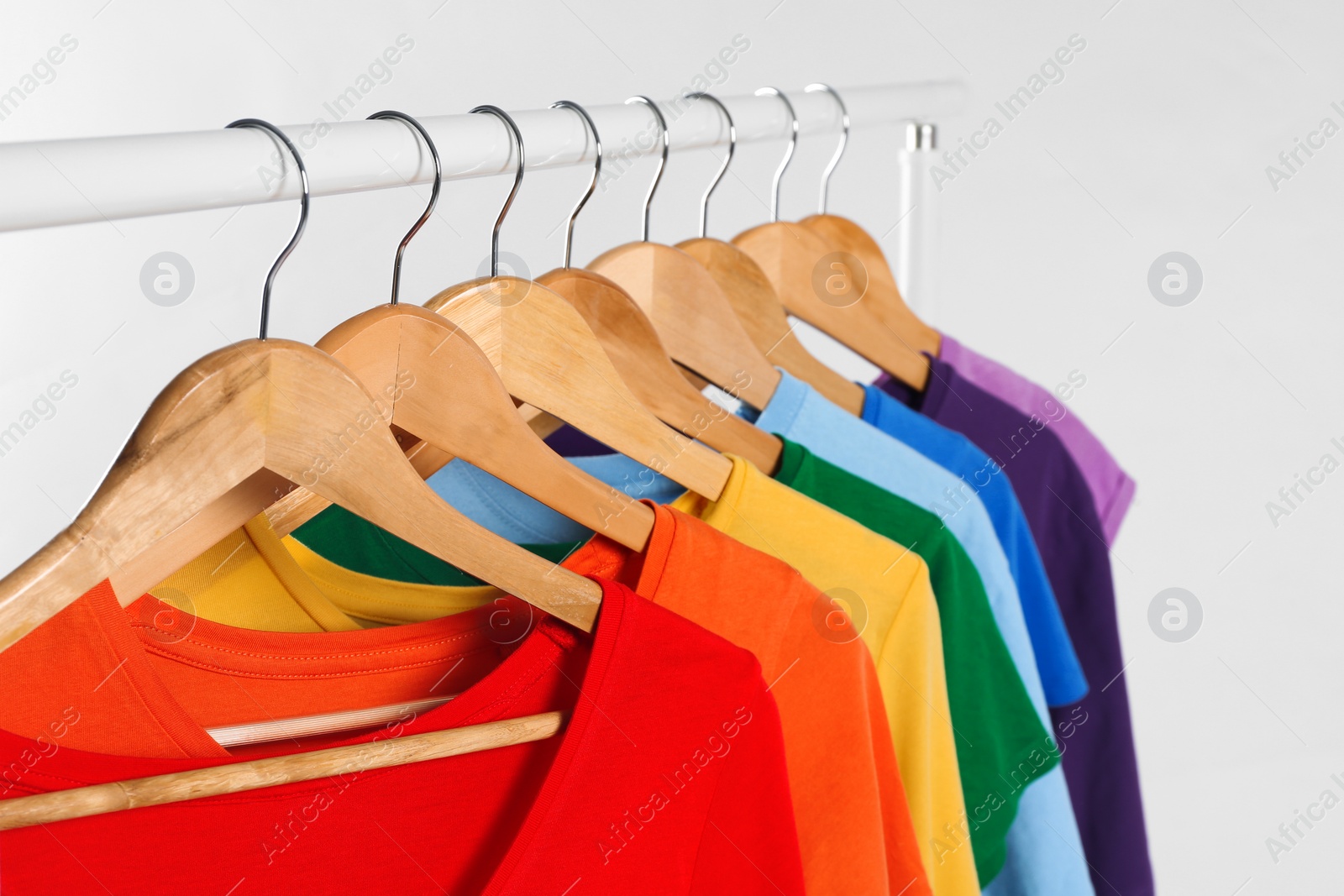 Photo of Colorful clothes on hangers against white background